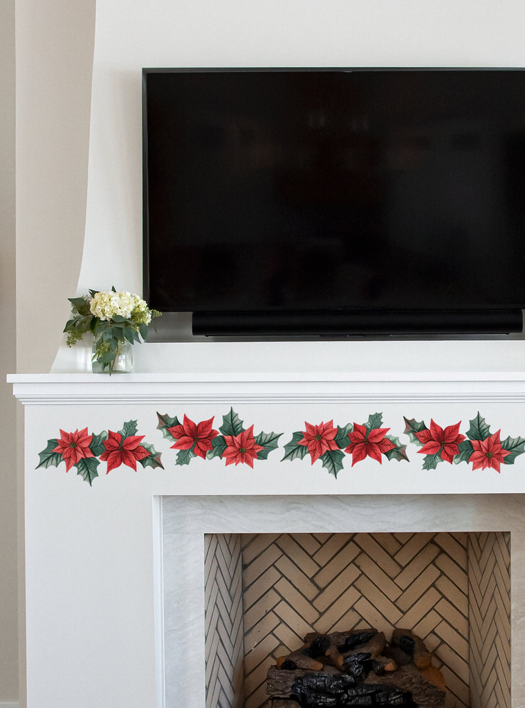 Festive Wreath Wall Sticker decorating a white fireplace mantel beneath a large TV, featuring vibrant red poinsettias and green leaves in a garland arrangement, adding holiday cheer to the living space. Wreath Wall Sticker, Top Sellers, Wall Stickers, All Products