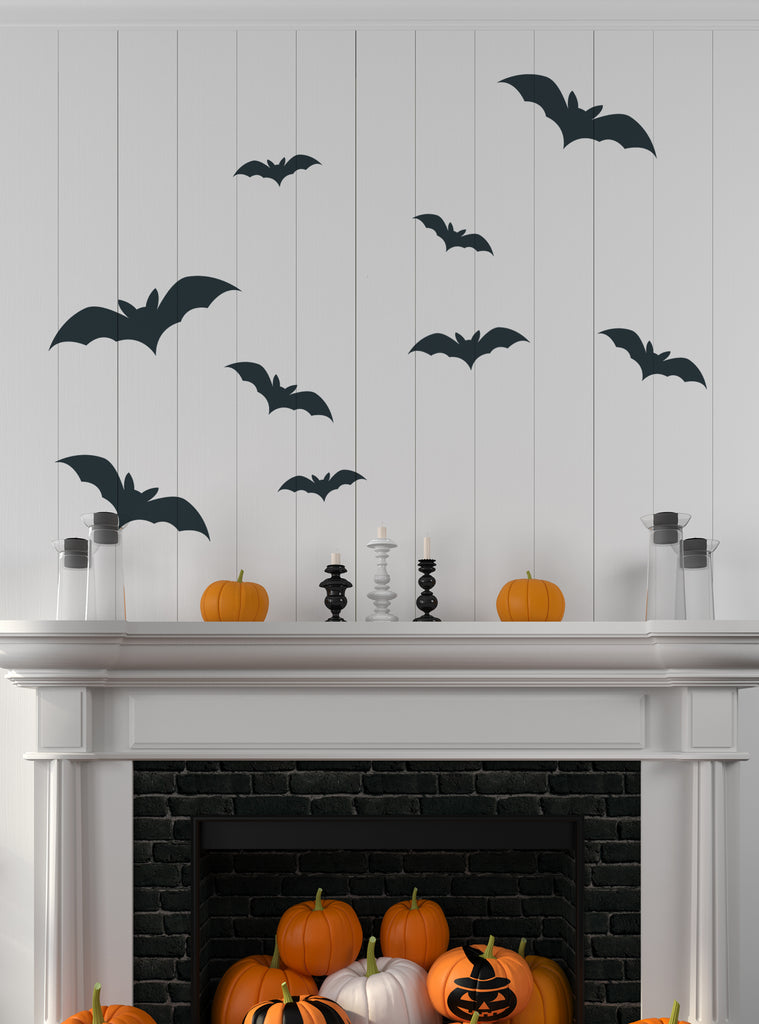 Spooky Bats Wall Decal displayed above a white fireplace mantel with Halloween decorations featuring nine black flying bats in various sizes arranged against a light gray wall, accompanied by decorative pumpkins and candleholders - Perfect Halloween Wall Decals for seasonal home decor. Featured Collection, Wall Decals, Holiday Decals and Stickers, All Products