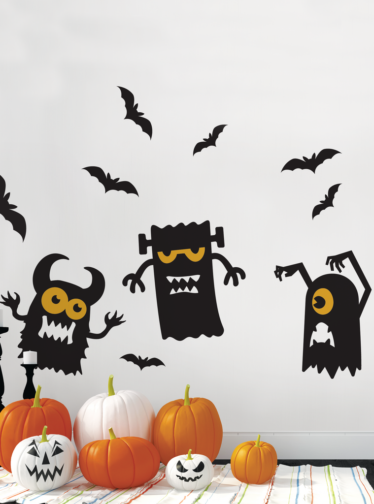 Halloween Monster Decals featuring playful black monster silhouettes with yellow glowing eyes, surrounded by flying bats, displayed above decorative orange and white pumpkins. Perfect wall decoration set for spooky yet fun Halloween home decor. Featured Collection, Wall Decals, All Products.