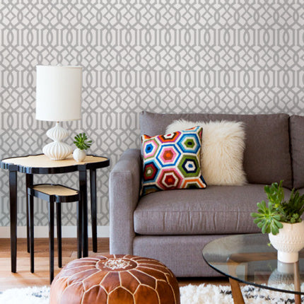 Decorative grey and white geometric pattern wallpaper covering the wall behind a cozy gray sofa with colorful patterned pillow, Avant Trellis Grey Fabric Peel and Stick Wallpaper OFF PRINT 24 x 108 Inches, Clearance Wallpaper Sticker - OFF PRINTS, Dorm Room Ideas and Trends