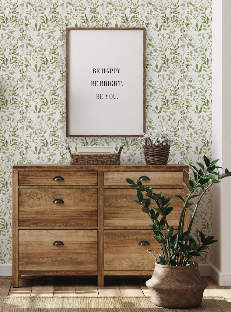 Watercolor Foliage Green Fabric Peel and Stick Wallpaper showcased in a cozy room setting with wooden dresser, inspiring framed quote, and potted plants. Perfect for transforming spaces with natural, fresh vibes. Clearance Wallpaper Sticker - OFF PRINTS, Dorm Room Ideas and Trends