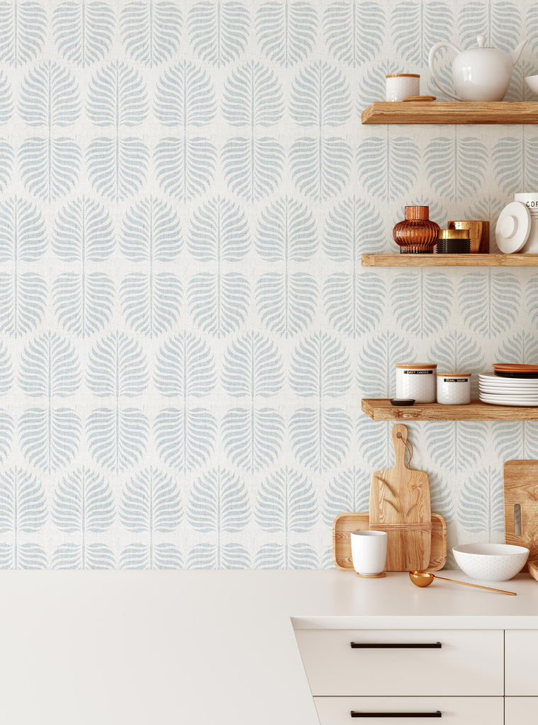 Fern Pattern Blue Fabric Peel and Stick Wallpaper OFF PRINT showcased in a bright kitchen with wooden shelves displaying kitchenware. The delicate blue fern pattern creates a soothing backdrop for the white countertop and kitchen accessories, perfect for small projects or dorm room makeovers. Clearance Wallpaper Sticker - OFF PRINTS, Dorm Room Ideas and Trends